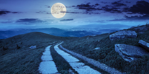 road on a hillside near mountain peak at night