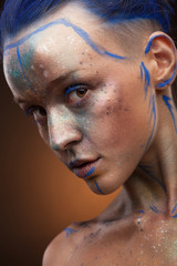 Portrait of a woman who is posing with blue and gold paint