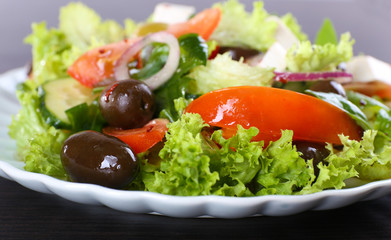 Greek salad in plate on wooden table background
