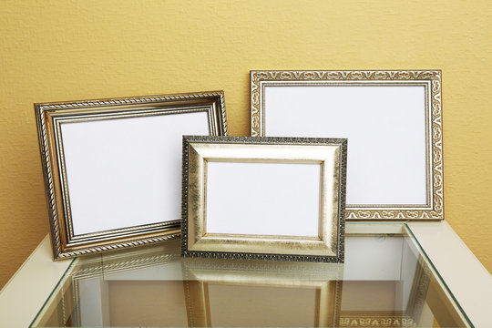 Vintage photo frames on coffee table on wallpaper background