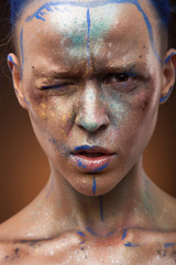 Portrait of a woman who is posing with blue and gold paint