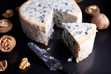 Blue cheese with nuts and blade on metal tray background