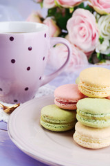 Colorful macaroons with cup of tea on wooden background