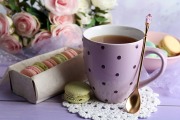Colorful macaroons with cup of tea on wooden background