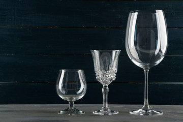 Empty glass goblets on dark color wooden background