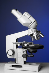 Microscope on table, on color background