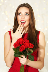 Smiling girl with bouquet of red roses on lights background