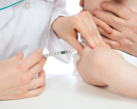 Doctors hand with syringe vaccinating child baby flu injection s