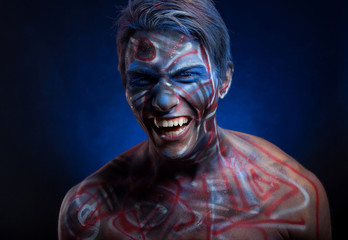 A creepy portrait of a man with bloody body art and face art