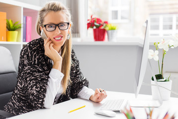 Creative young business woman talking on phone in office
