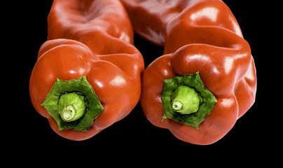 Closeup of two red paprikas, isolated on black.