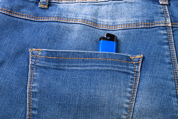 The pocket of jeans with lighter. Cloth background