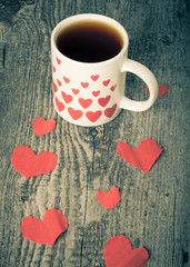 Valentine hearts and cup of tea on the old wooden table. Toned