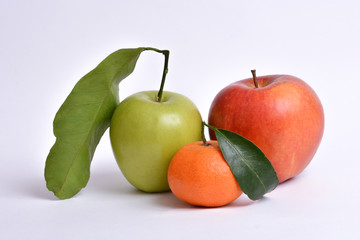 Green and red apples with leaves and orange mandarin