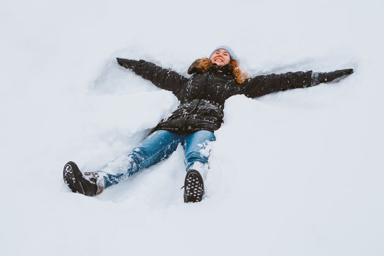 Portrait of a beautiful young woman creating a snow angel figure