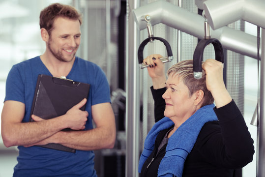 trainer betreut eine ältere frau im fitness-studio