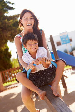 Mother And Son Having Fun On Seesaw In Playground