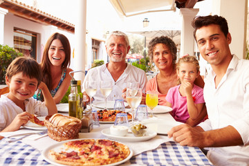 Multi Generation Family Eating Meal At Outdoor Restaurant