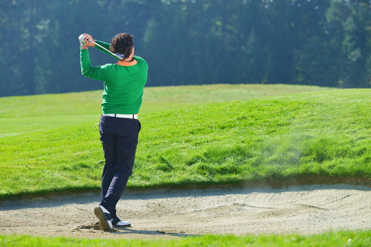 Golfer chipping the ball from sand trap, golf ball in the air.