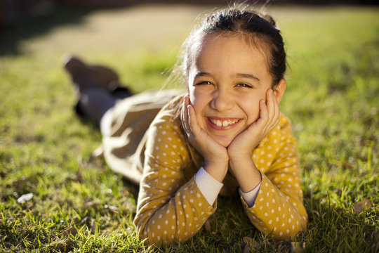 Ni&ntilde;a con vestido amarillo tumbada sobre el c&eacute;sped