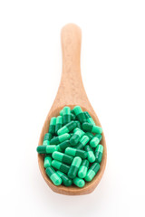 Pills drug on wooden spoon isolated on white background