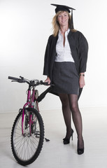 Fototapeta na wymiar Mature university student in cap and gown with her bicycle