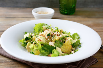 Fresh salad with avocado, orange and crushed nuts on a white pla