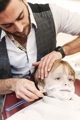 Obraz na płótnie Canvas child with shaving foam in the barbershop