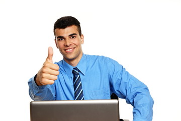 Young businessman sits at the laptop and shows you thumb up