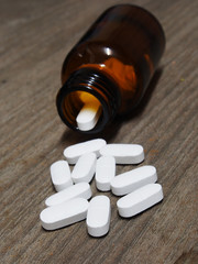 Pills spilling out of a pill bottle on wooden table