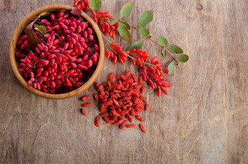 Obraz na płótnie Canvas Barberry with leaves and dry goji berries on wooden background
