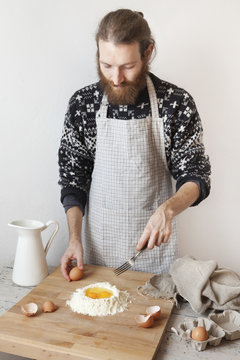 bearded stylish man with apron making dough for pasta