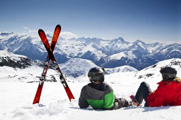 Fotobehang Wintersport Young happy couple lying in snowy mountains