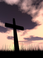 Black cross in grass ar sunset