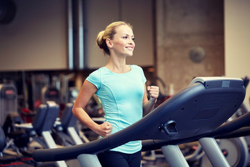 Fototapeta na wymiar smiling woman exercising on treadmill in gym