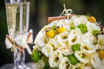 Wedding rings with wedding bouquet and glasses of champagne
