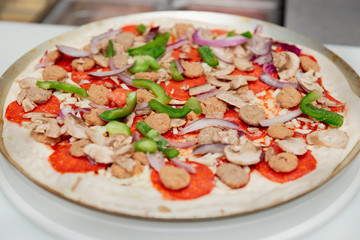 Raw pizza on metal platter