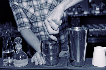 Fototapeta na wymiar Barman is muddling cocktail ingredients in shaker, toned