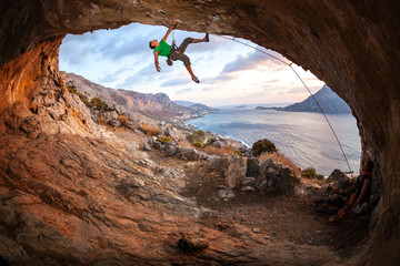 Young man lead climbing in cave before sunset