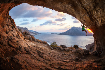 Young man lead climbing in cave before sunset