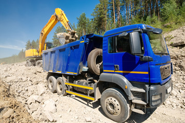 Dump Truck and Excavator in a Quarry. Building of the road.