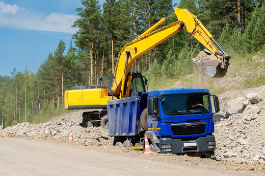 Dump Truck and Excavator in a Quarry. Building of the road.