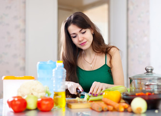 Obraz na płótnie Canvas beautiful housewife cutting vegetables at kitchen
