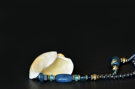 Seashell with blue necklace pearls isolated on black