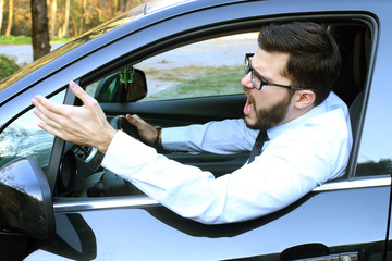 angry man driving a car and raising his hand violently