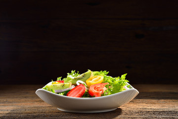 Fruit and vegetable salad in a bowl on wooden background