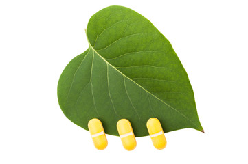 Three yellow pills on green leaf