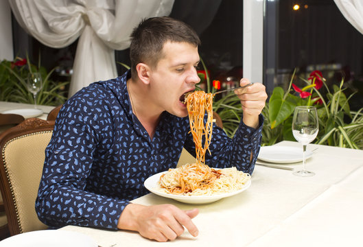 man eating a large portion of pasta in a restaurant