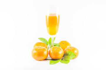 Pile of oranges with juice in glass on white background