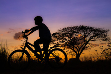 Silhouette of a children and bicycle on sunset